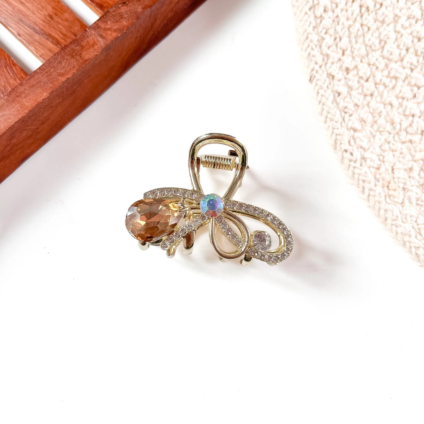 Amber/golden-brown gemstone metal claw clip with gold alloy filigree detailing and faceted amber teardrop jewel hanging from clip center.