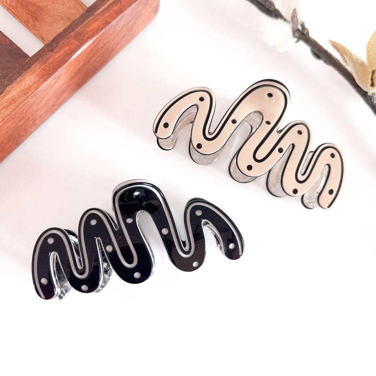 Both sculptural wave clips: ivory and black minimalist wave design with ribbed detailing