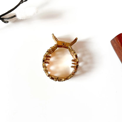 Close-up of amber faceted gemstones with rhinestone detailing on brushed gold metal