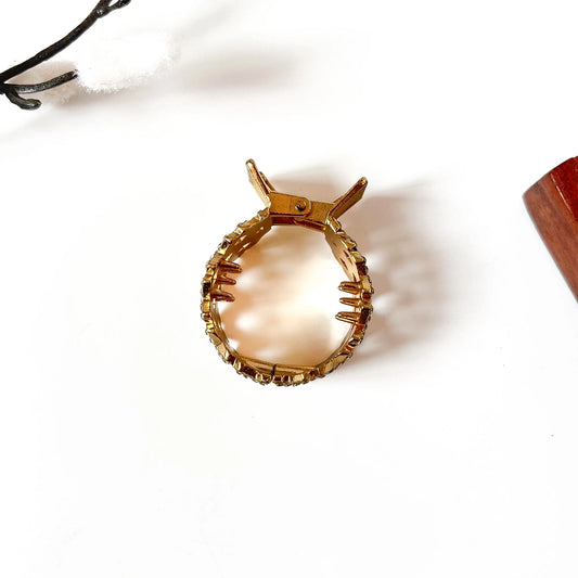 Close-up of amber faceted gemstones with rhinestone detailing on brushed gold metal