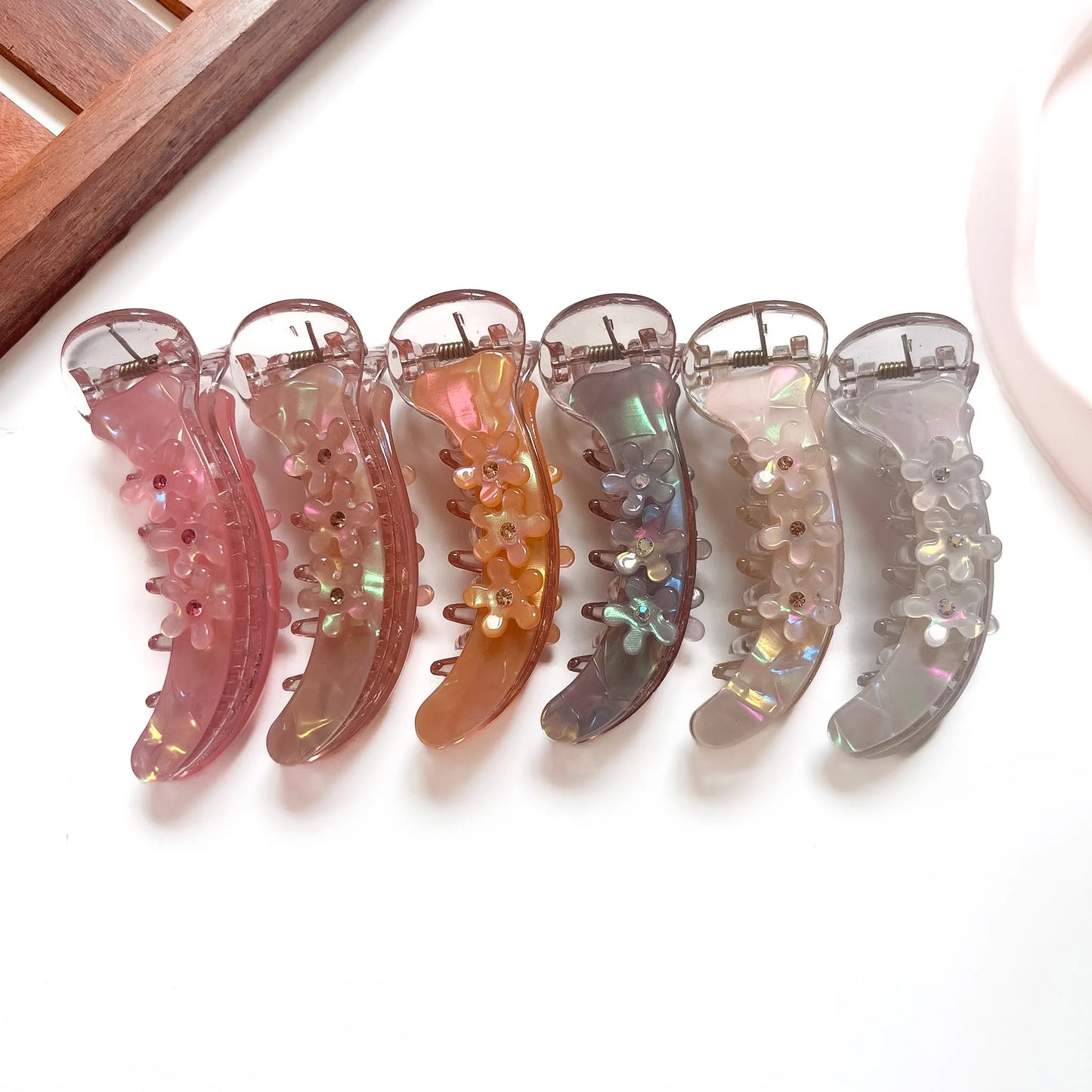Aurora daisy banana clips in hot pink, blush pink, amber, smoke blue, pearl and clear white with iridescent shimmer