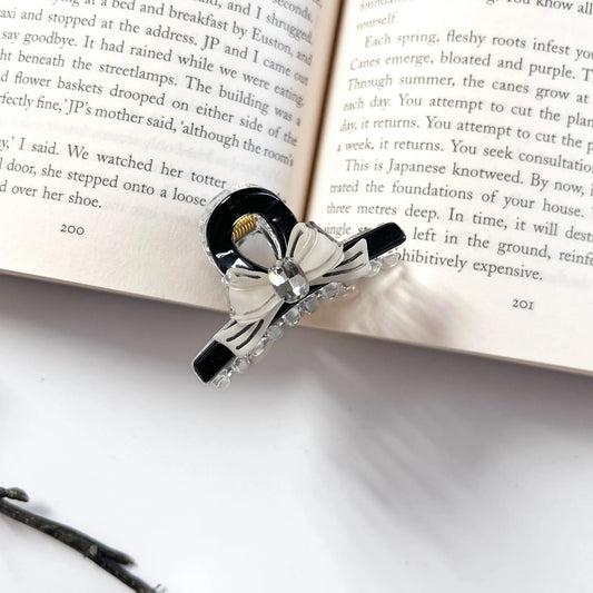 Black and white bow hair claw clip with rhinestone on open book