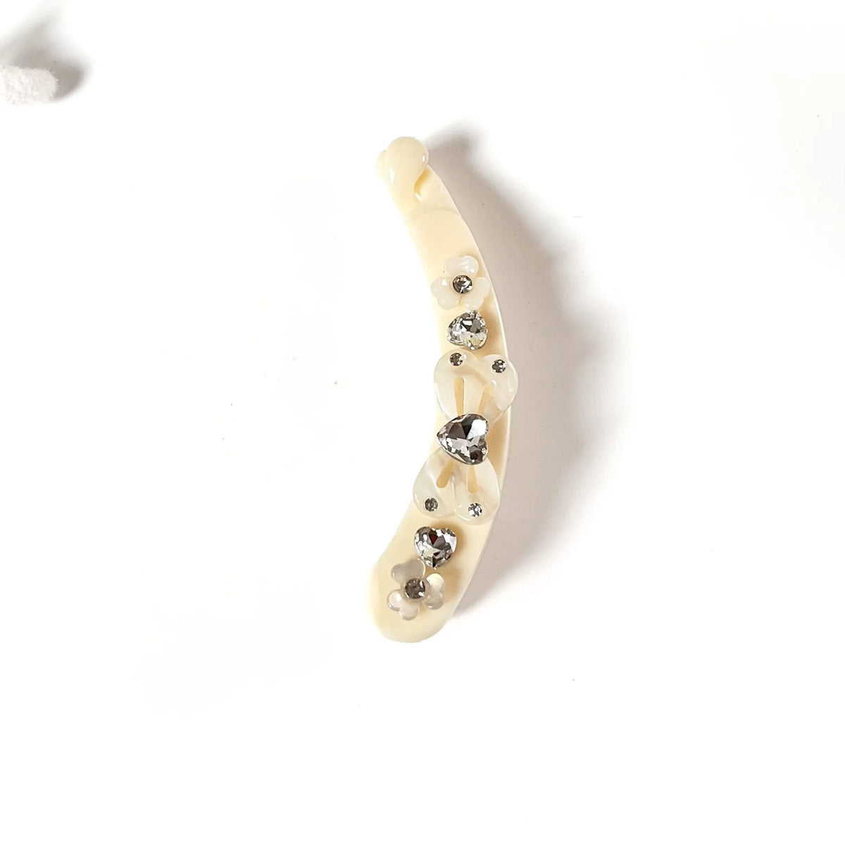 A curved cream-colored lock banana clip decorated with clear rhinestones, shown on a plain white background.