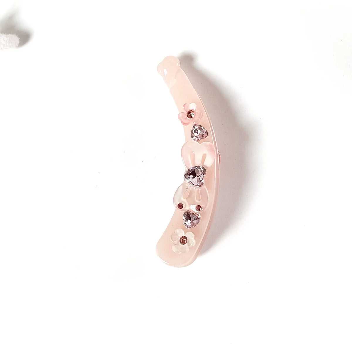 A pale pink curved lock banana clip decorated with small rhinestone flower embellishments, shown on a plain white background.