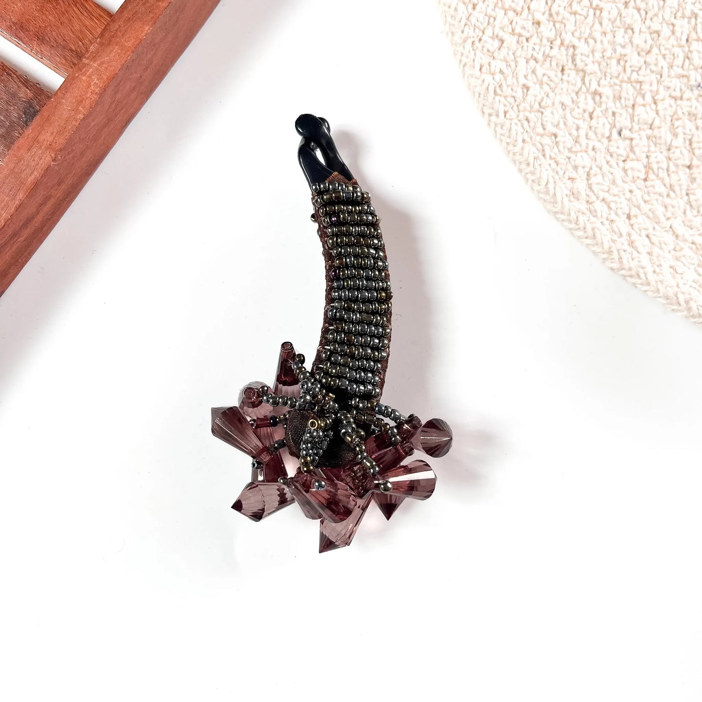 Brown crystalline banana clip with metallic beaded body and oversized rose-gold-toned gemstone embellishment.