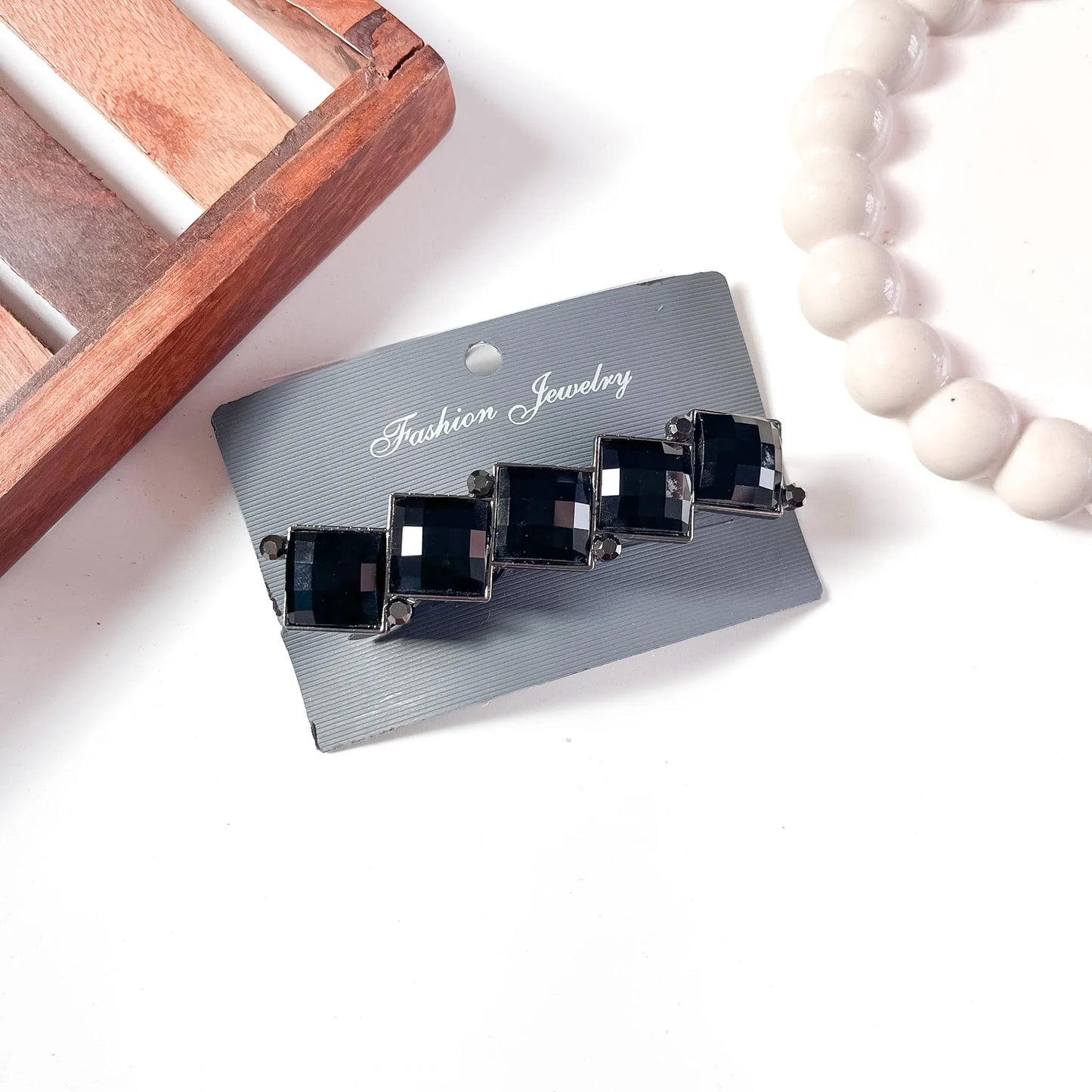 Black faceted cube gemstone center clip with deep onyx-tone stone and silver-tone metal trim on branded card.
