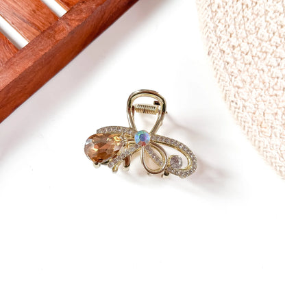 Amber/golden-brown gemstone metal claw clip with gold alloy filigree detailing and faceted amber teardrop jewel hanging from clip center.