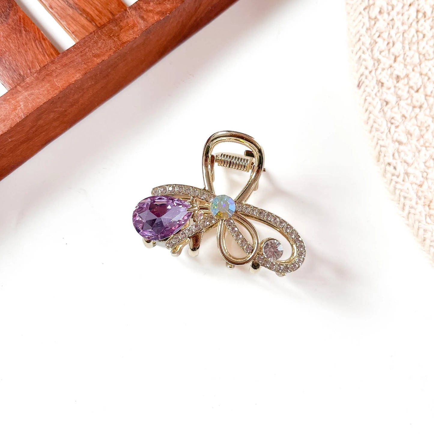 Purple gemstone metal claw clip with intricate filigree metal frame, purple faceted teardrop gemstone, and opal-toned center accent.