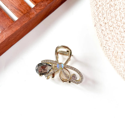 Smoky grey gemstone metal claw clip featuring ornate metal frame with hanging smoky faceted gemstone and iridescent bow accent.