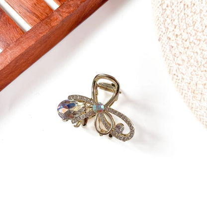 White opal gemstone metal claw clip with intricate gold-tone filigree, rainbow-tinted faceted teardrop, and shimmering opal centerpiece.