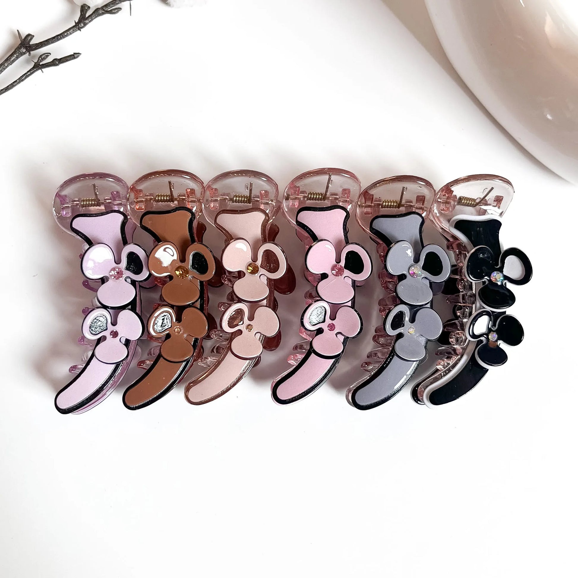 Graphic floral banana clips in lilac, brown, nude peach, pink, grey and black with bold enamel flower detail