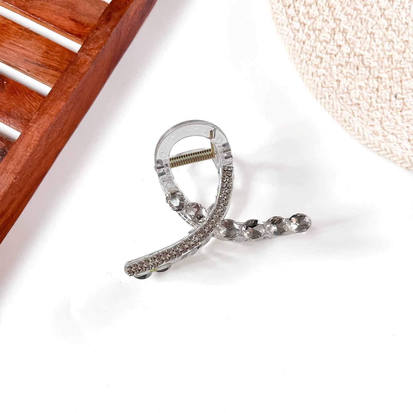 Large bow-shaped stone claw clip with clear rhinestone accents and silver metallic frame, displaying secure rectangular claw mechanism.