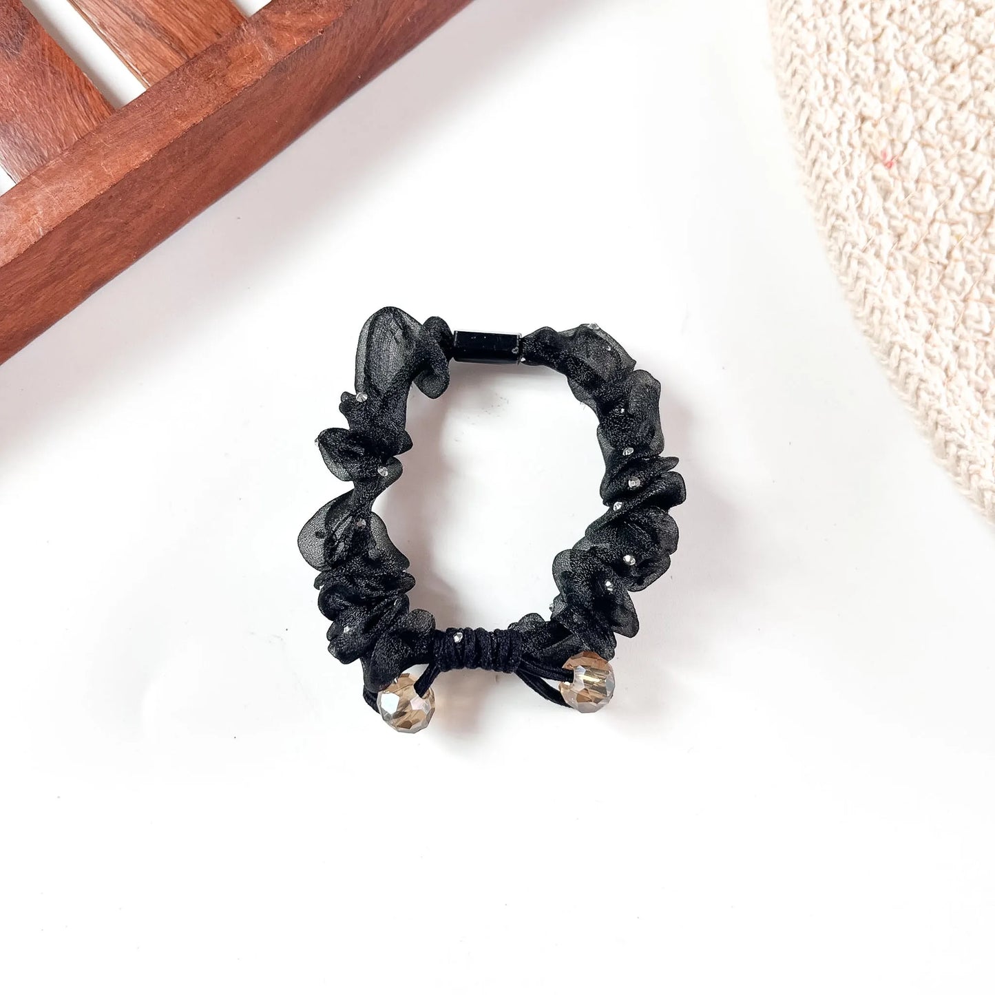 Black organza hair scrunchie featuring oversized sheer mesh ruffles and champagne crystal bead accents.