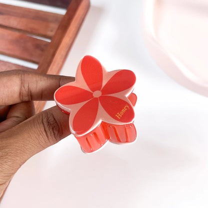 Hand holding red plumeria flower claw clip showing size of large floral claw clip