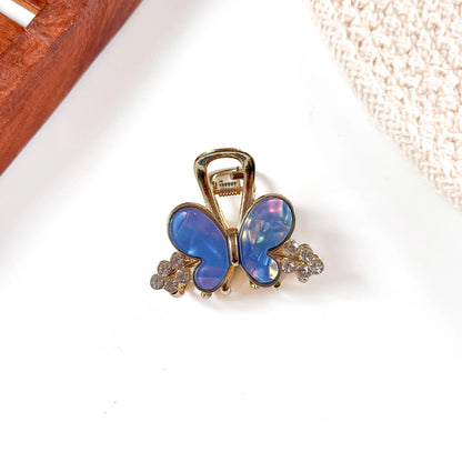 Sapphire blue resin butterfly metal claw clip with iridescent wing shimmer and gold-tone metal frame adorned with crystal accents.