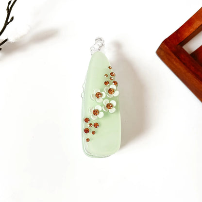 Sage green scattered gem banana hair clip with amber rhinestones and flower detail, large teardrop shape