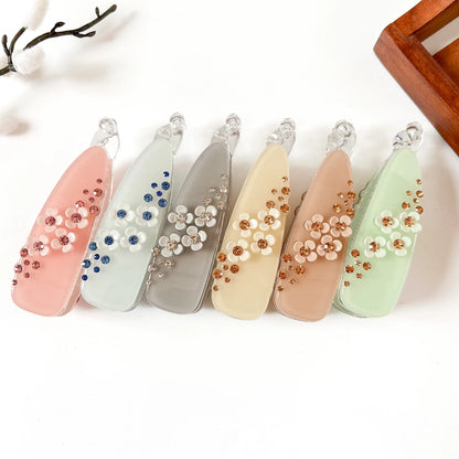 Set of 6 large teardrop banana clips in blush pink, sage green, slate blue, vanilla cream, cognac peach, and mint green. Each with scattered gem rhinestones and white flower center accent. Perfect for thick hair, curly hair, and fine hair. Large fancy banana hair clips.