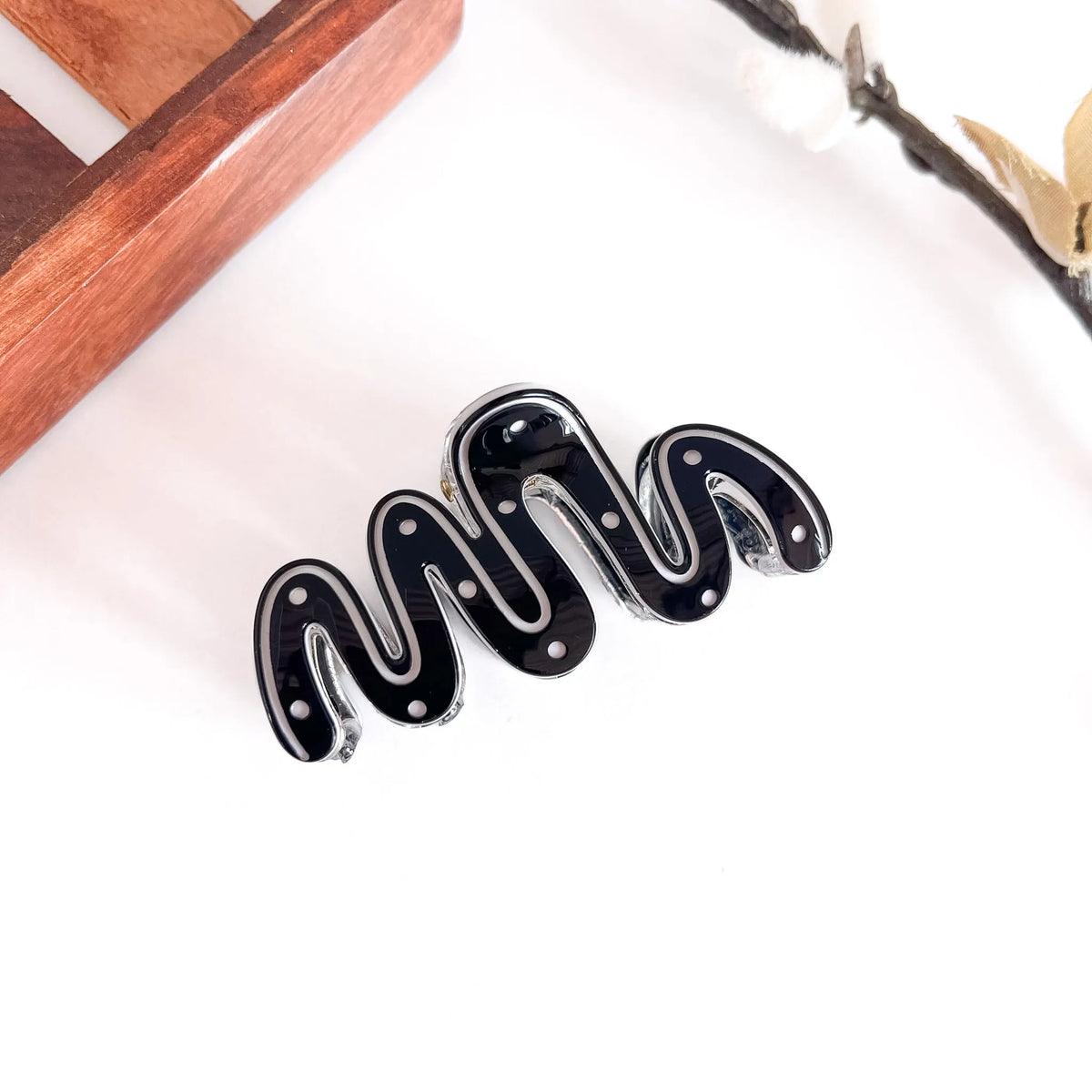 Black sculptural wave hair clip with polished ribbed texture, medium contemporary geometric clip