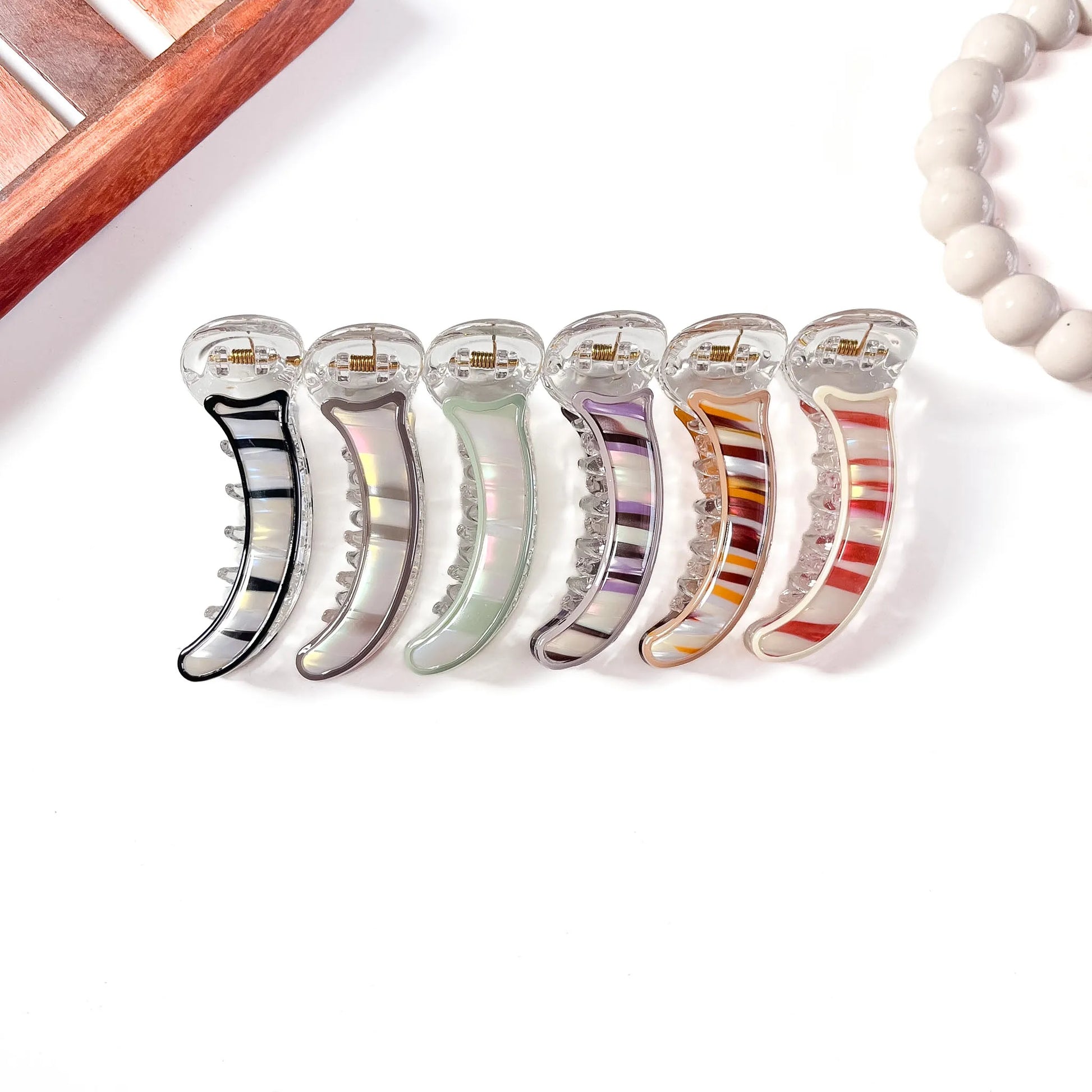 Set of five clear hair banana clips with colorful interior designs on a white surface.