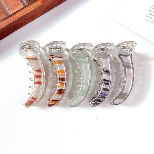 Set of five clear hair banana clips with colorful interior designs on a white surface.